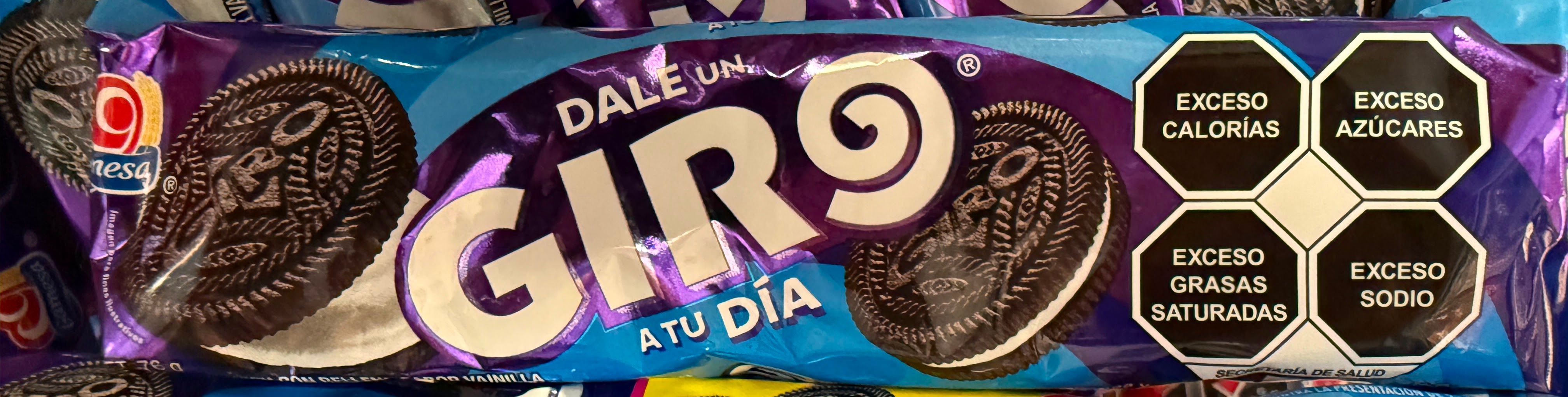 A Mexican 'GIRO' cookie package with bold black octagonal warning labels reading EXCESO CALORÍAS, EXCESO AZÚCARES, EXCESO GRASAS SATURADAS, and EXCESO SODIO.
