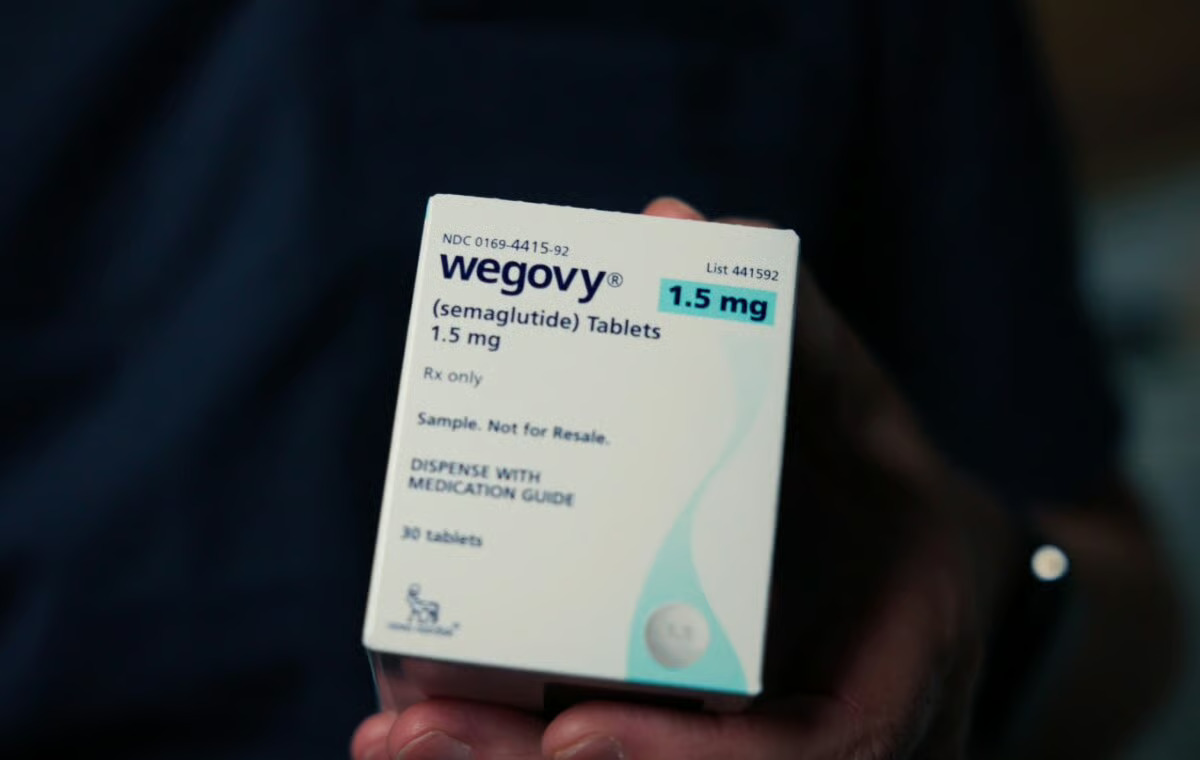 A hand holds a Wegovy (semaglutide) oral tablet package — 1.5 mg, 30 tablets — in front of a dark background.