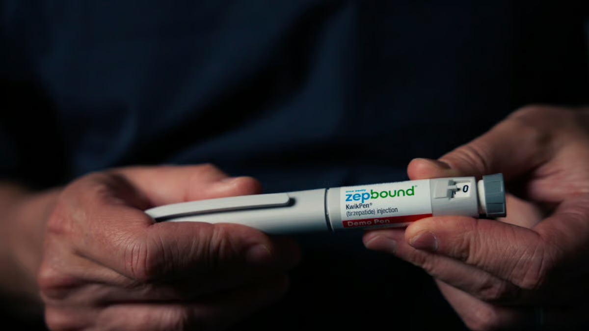Hands hold a capped Zepbound KwikPen demo pen, showing the label and dose dial.