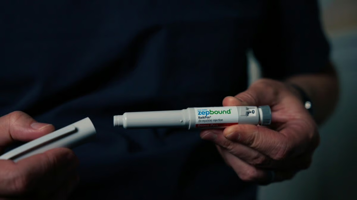 Hands hold an uncapped Zepbound KwikPen demo pen, showing the needle end of the device.